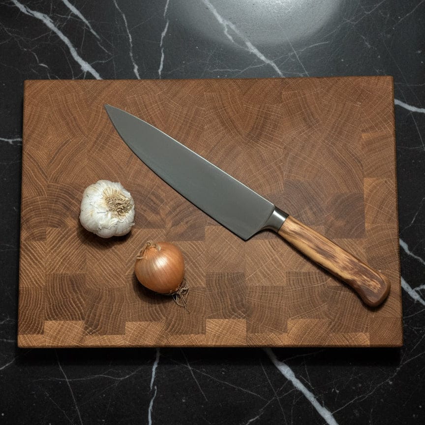 Stirnholz Schneidebrett mit Messer darauf und Knoblauch und zwiebel