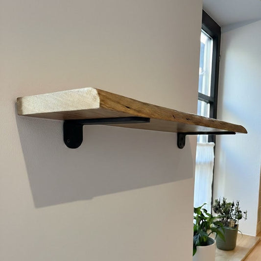 Massives Eichenholz Wandregal an weißer Wand mit schwarzen Regalhalterungen von unten